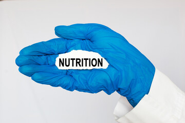 The doctor's blue - gloved hands show the word NUTRITION - . a gloved hand on a white background. Medical concept. the medicine