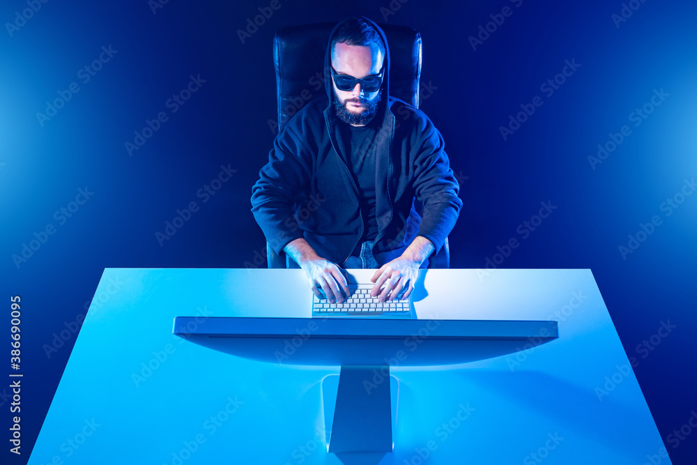 Poster portrait of a man at a computer. blue photo of the programmer from above. a man is typing on a compu