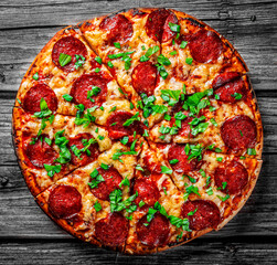 Pepperoni Pizza with Mozzarella cheese, salami, Tomato sauce, pepper, Spices and Fresh basil. Italian pizza on wooden table background