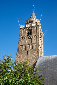 The roman tower of the Protestant church an the gray slated roof located in the centre of the South-Holland village of Rijnsburg in the Netherlands. On a clear blue and sunny day.