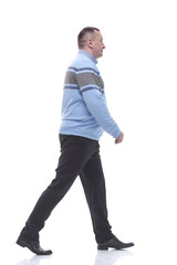 side view. a serious man in a sweater walks forward