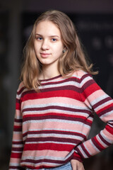 Young beautiful girl in a striped sweater posing on a dark background.