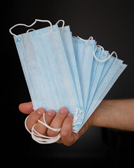 male hand holding several disposable medical masks. selective focus 