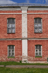 Fototapeta na wymiar Brick facade of an old building with four Windows and a metal roof
