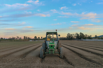 Obraz premium Tractor en campo arado al atardecer en Churriana, Málaga