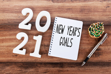 2021 New Year's Goal text on notepad with pen, mini Christmas tree and wooden number