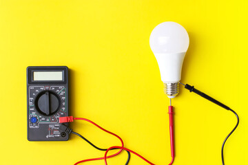 White glowing light bulb Dark Digital multimeter with probes. Power energy economy concept.