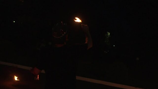 Man shows dangerous tricks with fire in fire show at night, background, slow mo