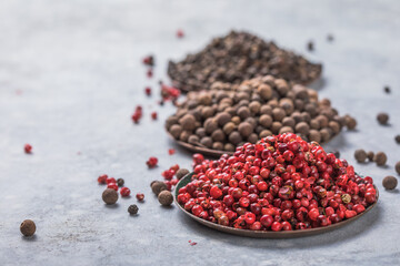 Various kinds of peppercorns in bowls on  stone background
