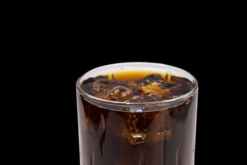 Close up view of top of full glass of soda with ice cubes isolated on black background. Unhealthy drinks concept. Health concept. Beverage concept.