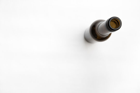 Einzelne leere braune Bierflasche auf wei&szlig;em Untergrund, von oben, Perspektive