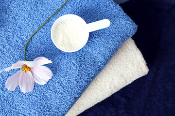  Multi - colored Terry towels with washing powder and a bouquet of delicate flowers, top view-the concept of General washing in the house