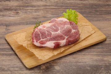 Raw pork steak over wooden board