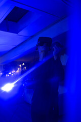 A man at home wearing virtual reality glasses. Holds controllers in his hands. Guy plays vr games. Neon lights