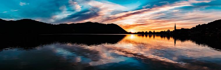 Obraz premium High resolution stitched panorama of a beautiful alpine sunset view with reflections and dramatic clouds at the famous Schliersee, Bavaria, Germany
