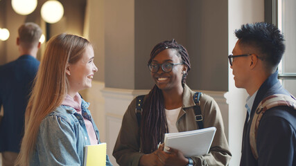 Happy college friends laughing joyfully talking in campus building