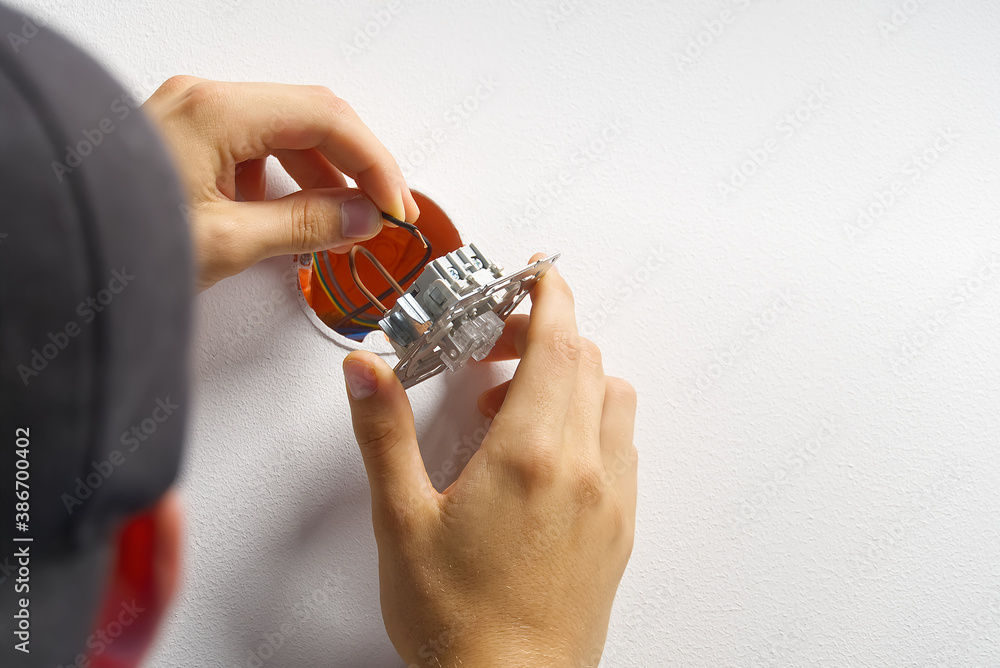 Poster electrician installing light switch on painted wall with screwdriver. man installing light switch af