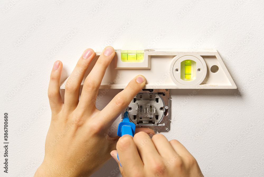 Poster electrician installing light switch on painted wall with screwdriver. man installing light switch af