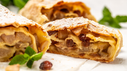 Home autumn, summer baking, puff pastries. Apple strudel with raisins, cinnamon and powdered sugar mint on light background. view from above, banner format