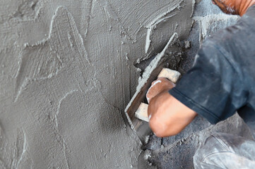 closeup hand of worker plastering cement at wall in construction site - obrazy, fototapety, plakaty