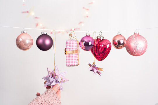 Christmas picture with different balls in colors of berries. Small gift and tree pendant hanging on a string. The hand of a woman touches a Fröbelstern.