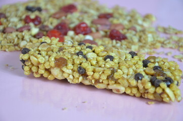 Granola bars, muesli bars or energy bars with oats, dates and nuts on white pink background, close up. Snack for yoga, fitness and sports people, fitness bar, diet concept