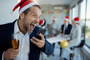 Drunk businessman screaming on cell phone while making a phone call during Christmas party in the office.