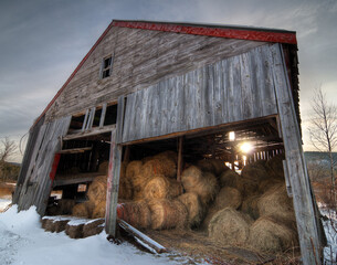 Old barn with hay bales with snow in winter © Andrew
