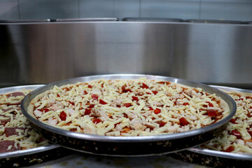 view of preparation of pizza in kitchen with red bell pepper and chicken with cheese