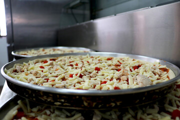 view of preparation of pizza in kitchen with red bell pepper and chicken with cheese