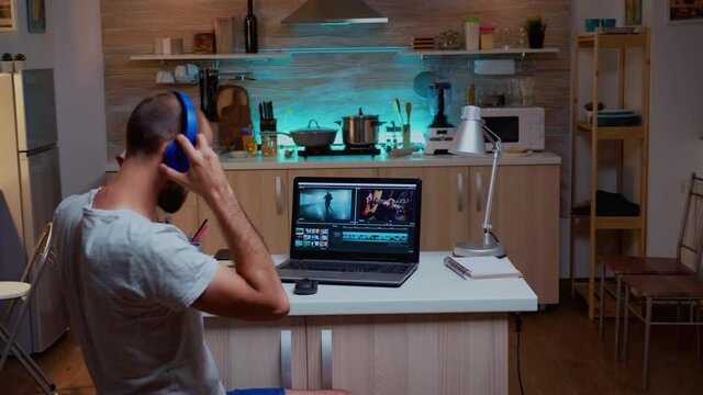 Creative filmmaker editing video footage in home using modern technology. Man content creator in home working on montage of film in new software for editing late at night.