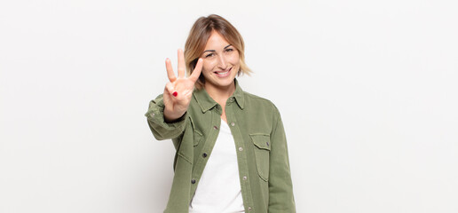 young pretty woman smiling and looking friendly, showing number three or third with hand forward,...