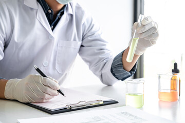 Scientist or medical in lab coat holding test tube with reagent, mixing reagents in glass flask,...