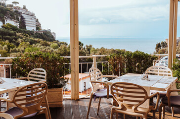 Beautiful Sorrento sea view from a restaurant terrace with empty tables and stylish beige chairs