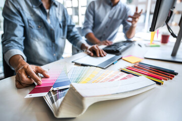 Young colleagues designers working together on a creative project and color samples for selection,...