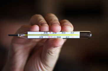 Mercury thermometer in hand with normal temperature 36.6, close-up