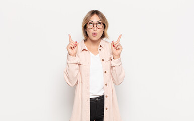 young pretty woman feeling awed and open mouthed pointing upwards with a shocked and surprised look