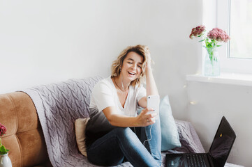 a girl blogger communicates with her subscribers, sitting at home on a cozy sofa with headphones.