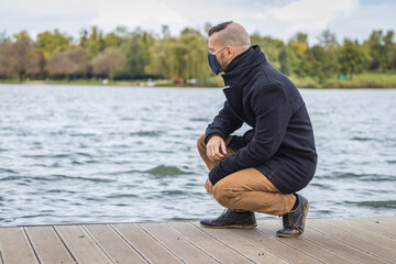 A man in a mask in the park at a lake