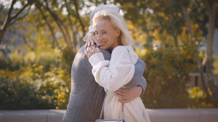 Happy senior man and woman meeting in autumn park and embracing with joy