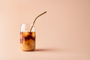 Glass of iced coffee in tall glass with golden straw with cream on pastel background for your design. Food concept in vintage style. Copy space. Closeup.