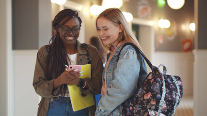 Diverse college friends watching video on smartphone and laughing