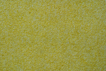 Yellow ocher stucco texture on exterior wall with fine grains. Yellow sandpaper background macro