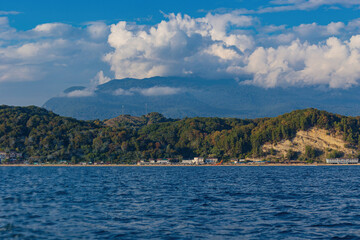 View from the sea on a boat to the city near the mountains with beautiful clouds .