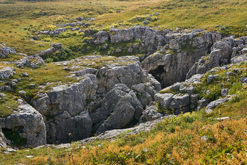 Fototapeta na wymiar karst hole in the middle of the autumn alpine meadow