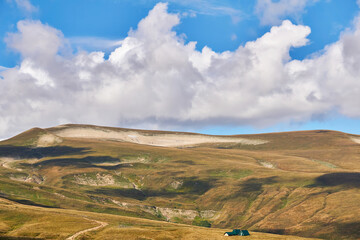 mountain landscape with autumn alpine meadows, beautiful clouds and a tourist shelter