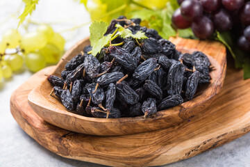 Black raisins  in bowl on stone  background, table top view. Dried fruit, healthy snack food