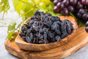 Black raisins  in bowl on stone  background, table top view. Dried fruit, healthy snack food