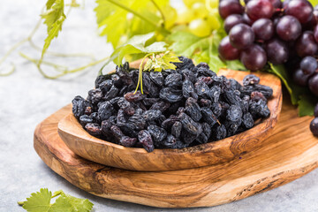 Black raisins  in bowl on stone  background, table top view. Dried fruit, healthy snack food