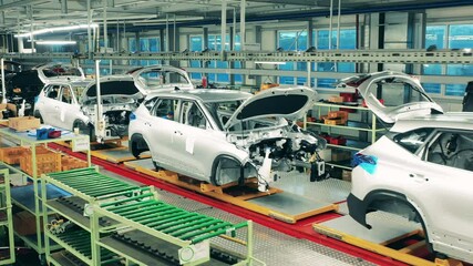 Unfinished automobiles put in a row in the factory facility. Car assembly line, automobile industry concept.